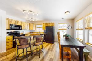 eine Küche mit einem Holztisch und einem schwarzen Kühlschrank in der Unterkunft Fox Bay Escape in Heber City