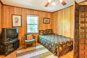 Schlafzimmer mit einem Bett, einem TV und einem Stuhl in der Unterkunft Lakefront Mountain Rest Cottage with Gas Fireplace! in Walhalla