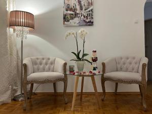 2 sillas, una mesa y una lámpara en una habitación en Louis & Elza Old Town Romantic apartments, en Wroclaw