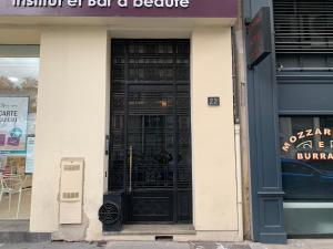 una puerta negra de una tienda con un cartel delante en Au Coeur De Lyon en Lyon