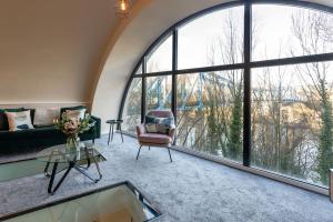 Stylish Duplex 5 min from centre في نيوكاسل أبون تاين: غرفة معيشة بها أريكة وكرسي ونوافذ كبيرة