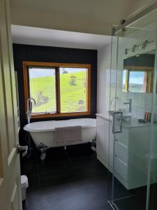 a bathroom with a bath tub and a window at Maple Ridge Cottages in Dumbalk