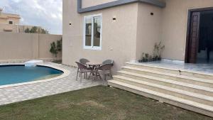 una casa con tavolo e sedie accanto a una piscina di فيلا محمد بدر ad Alessandria d'Egitto