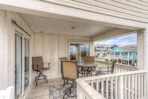 een veranda met een tafel en stoelen op een balkon bij Windward in Carolina Beach