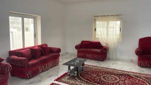 فيلا محمد بدر في الإسكندرية: غرفة معيشة بها كنبتين حمراء وطاولة