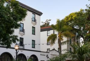 a white building with a palm tree in front of it at Hotel Santa Barbara in Santa Barbara