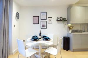 a white dining room with a white table and chairs at A beautiful one bedroom flat with garden & parking in Mill Hill