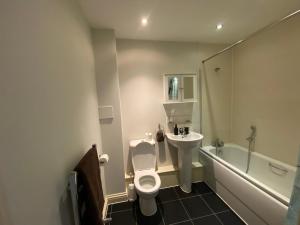 a bathroom with a toilet and a sink and a tub at Rooms in exquisite and centrally located apartment in Colindale