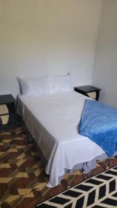 1 dormitorio con cama blanca y manta azul en Kingstonspot876, en Kingston
