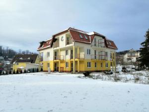 a yellow and white house in the snow at Levendula Apartman Bükkszentkereszt in Bükkszentkereszt