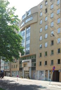 een groot gebouw op een straat met een boom bij Ambassador Suites Antwerp in Antwerpen