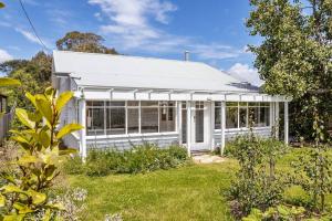 a white house with a garden in front of it at Balmoral Cottage - beach escape in Kingston Beach