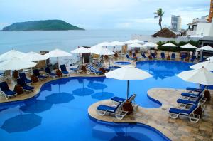 a large swimming pool with chairs and umbrellas at Royal Villas Resort in Mazatlán