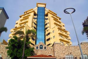 a tall yellow building with palm trees in front of it at Royal Villas Resort in Mazatlán