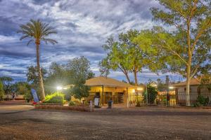 a building with a palm tree in front of it at Outback Caravan Park Tennant Creek in Tennant Creek