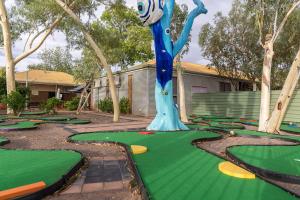 a golf course with a statue of a character on a putting greens at Outback Caravan Park Tennant Creek in Tennant Creek