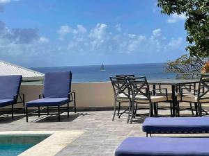 eine Terrasse mit einem Tisch, Stühlen und Meerblick in der Unterkunft Villa Zircon in Pelican Key awaits you in Koolbaai