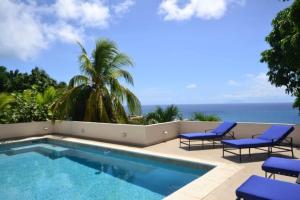 einen Pool mit Stühlen und das Meer im Hintergrund in der Unterkunft Villa Zircon in Pelican Key awaits you in Koolbaai