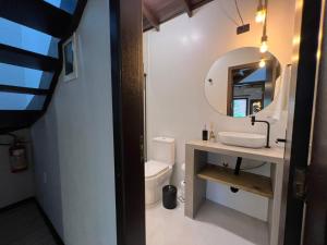 a bathroom with a sink and a mirror and a toilet at Pousada Flor de Lotus in Praia do Rosa