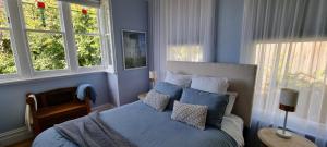 1 dormitorio con 1 cama con paredes y ventanas azules en Hill House Hobart - Charming home, stunning views close to city en Hobart