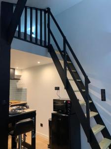 a staircase in a room with a desk and a kitchen at Studio indépendant avec mezzanine in Provins