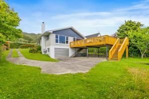 a house with a large yard with a wooden deck at Winara Winner - Waikanae Holiday Home in Waikanae