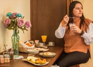 una mujer sentada en una mesa comiendo comida con un tenedor en Pousada Medeiros, en Monte Verde
