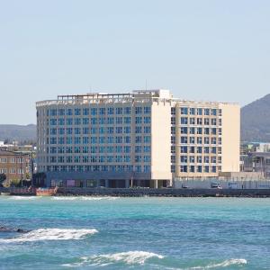 a large building in front of the water with a building at Saint Beach Hotel in Jeju
