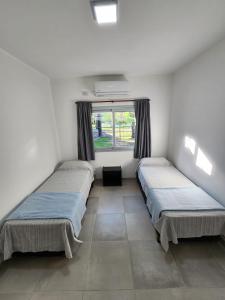 two beds in a room with a window at BAHIA de los PESCADORES in Paso de la Patria