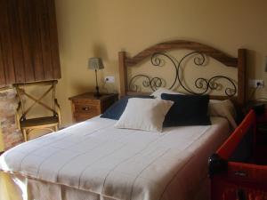 um quarto com uma grande cama branca e uma cabeceira em madeira em La Posada de Toribia em Val de San Lorenzo