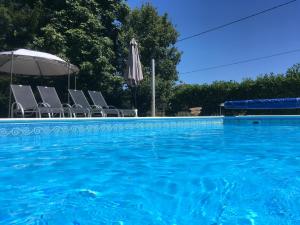 - une piscine avec des chaises et un parasol dans l'établissement Le Petit Chateau, à Brouchaud