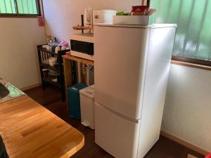 Un refrigerador blanco en una cocina con microondas. en 奄美 大和宿 AMAMI yamato INN,  12 fotos más