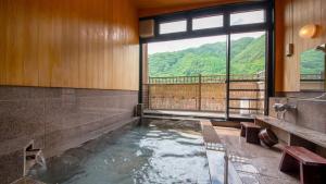 a bathroom with a pool of water with a window at Yamamizuki Urara Tsutaya in Kiso