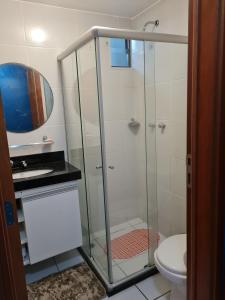La salle de bains est pourvue d'une douche en verre et de toilettes. dans l'établissement Apartamento Edifício Edécio Lopes, à Maceió