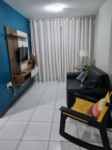 sala de estar con sofá negro y TV en Apartamento Edifício Edécio Lopes, en Maceió