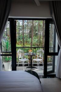 1 dormitorio con 1 cama y balcón con mesa y sillas en Casa Vanilla Mang Den, en Kon Von Kla