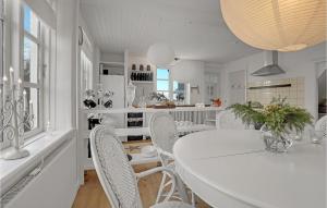 a white dining room with a white table and chairs at Amazing Home In stermarie With 3 Bedrooms And Wifi in Østermarie