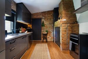 a kitchen with black cabinets and a brick wall at The Nook in Daylesford