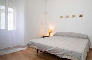 um quarto branco com uma cama e um candeeiro sobre uma mesa em Apartamento deluxe Terraza y bbq em Santa Amalia