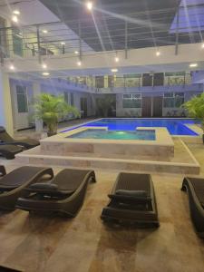 a large swimming pool with lounge chairs in a building at Hotel Cayuga in Puntarenas