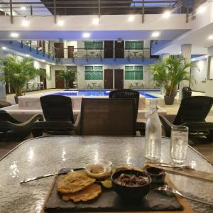 una mesa con una bandeja de comida con una piscina en Hotel Cayuga en Puntarenas