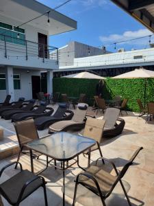 eine Terrasse mit Stühlen, Tischen und Sonnenschirmen in der Unterkunft Hotel Cayuga in Puntarenas