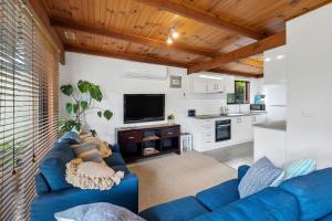 a living room with blue couches and a kitchen at Magic on Murray in Anglesea