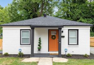 una pequeña casa blanca con puerta naranja en Art Deco Inspired Bungalow 7 mins from Uptown, en Charlotte