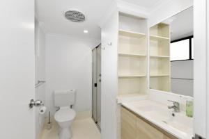 a white bathroom with a toilet and a sink at Allamanda Unit 22 in Long Jetty