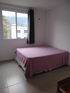 a bedroom with a pink bed and a window at Condomínio Ilha do Sol in Florianópolis