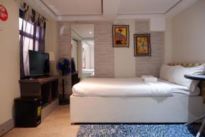 1 dormitorio con 1 cama blanca grande y TV en Sunset View Ridge Residences, en Baguio