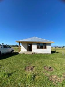 a white house with a car parked in front of it at Cabañas del Llano in Puyehue
