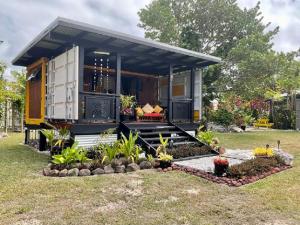 a tiny house with a porch in a yard at Are Mii a stylish one room container home in Rarotonga