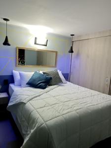 1 dormitorio con 1 cama blanca grande y 2 almohadas en Apartamento con vistas a la ciudad (Penthouse) cerca al Estadio, al Boulevard de la 70 y la Avenida 80 (Casinos, restaurantes, malls y otros)., en Medellín